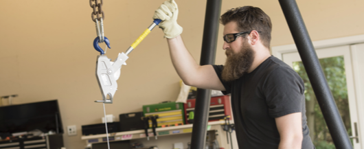 Man using a crane hook in a workshop setting